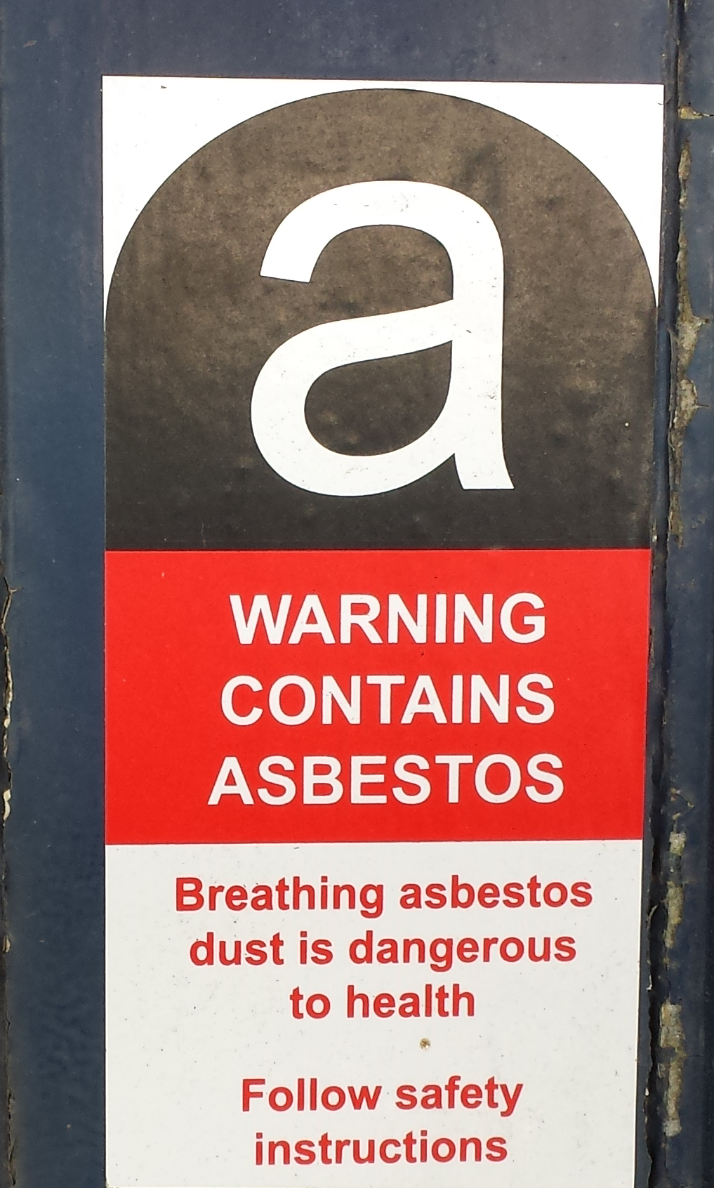 The UK asbestos warning label: a white letter a on black, above the words Warning contains asbestos
