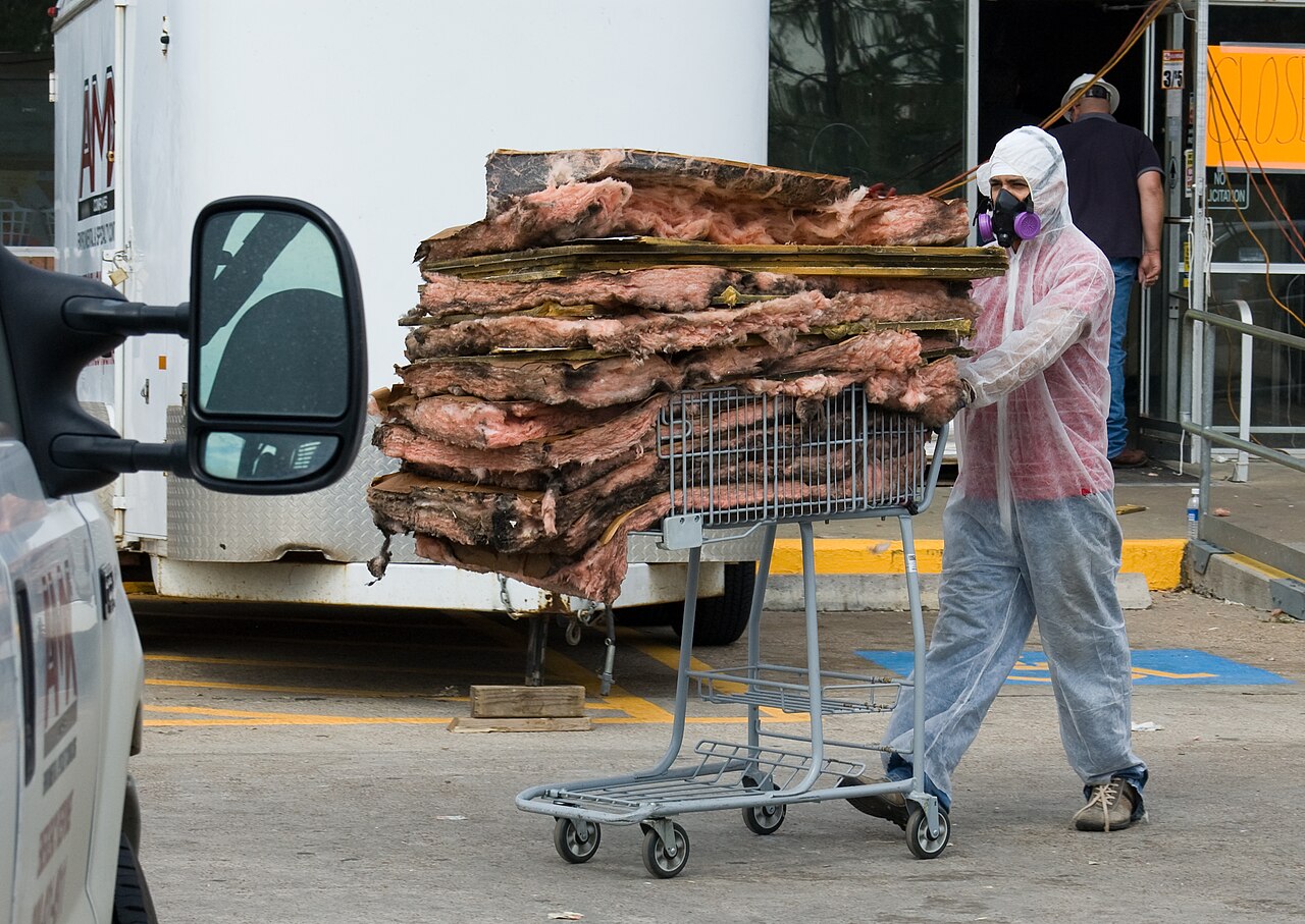 A worker in a protective coverall and respirator of the kind used for asbestos survey and sampling work
